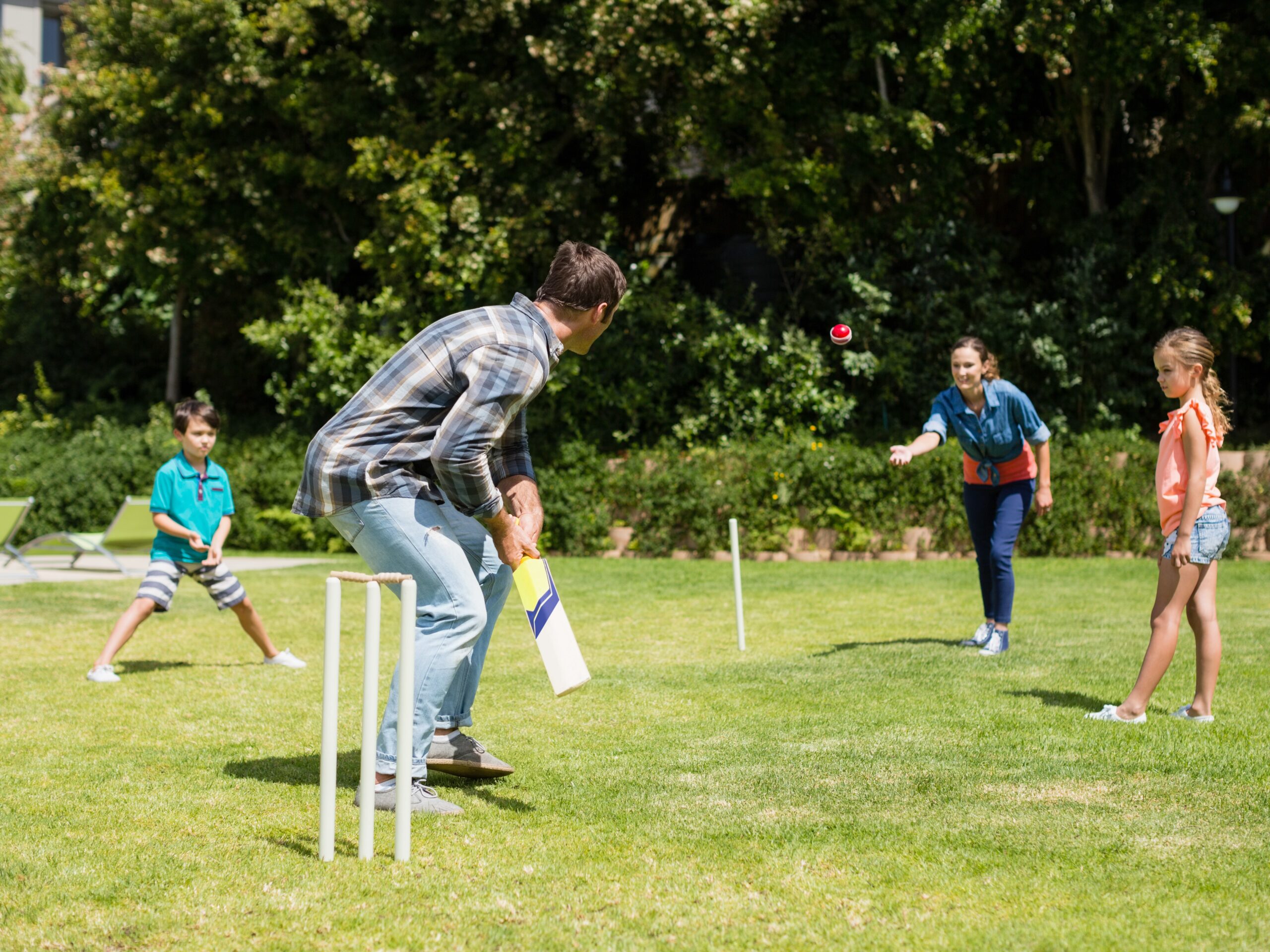 Happy family playing cricket in park on a sunny day
